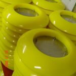 Yellow plastic rings stacked in workshop with technical drawings.