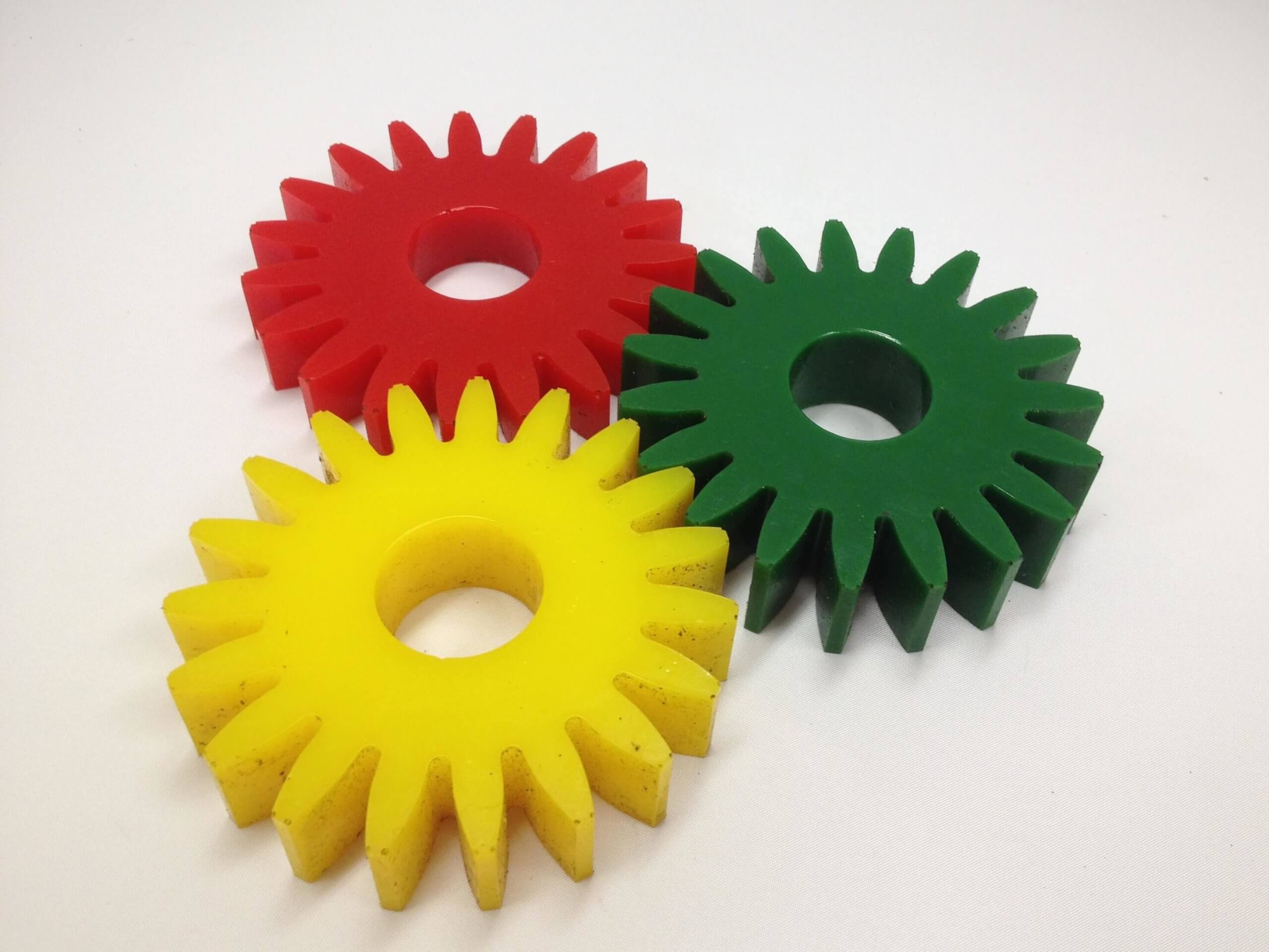 Three colorful, plastic gears overlap on a white background.