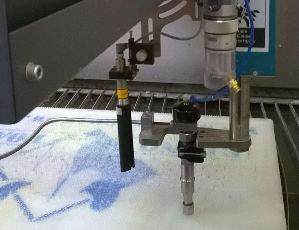 Machine arm positions tool over cutting surface in workshop.