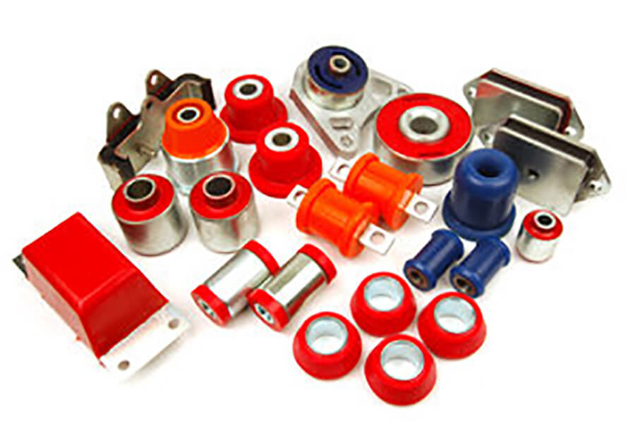 Various colorful automotive bushings arranged on a white surface.