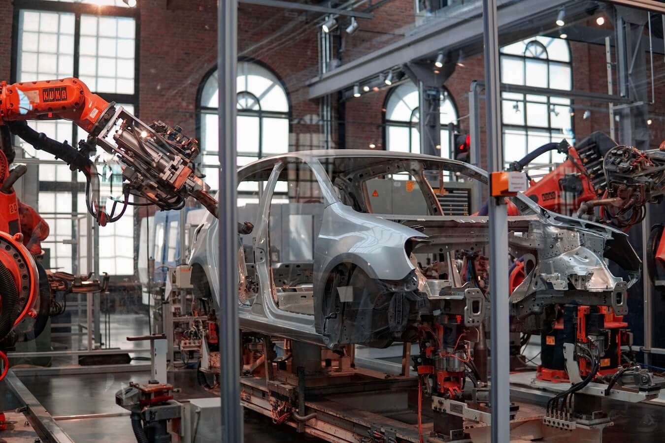 Robotic arms assemble car frame in an industrial factory.