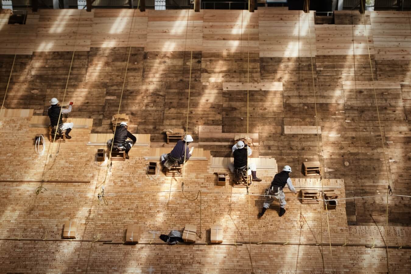 Workers installing wooden panels on large, light-filled surface.
