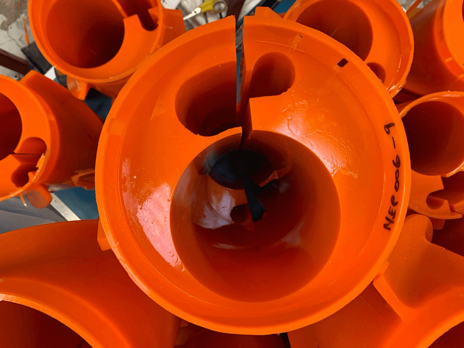 Orange traffic cones stacked vertically with written label, outdoor setting.