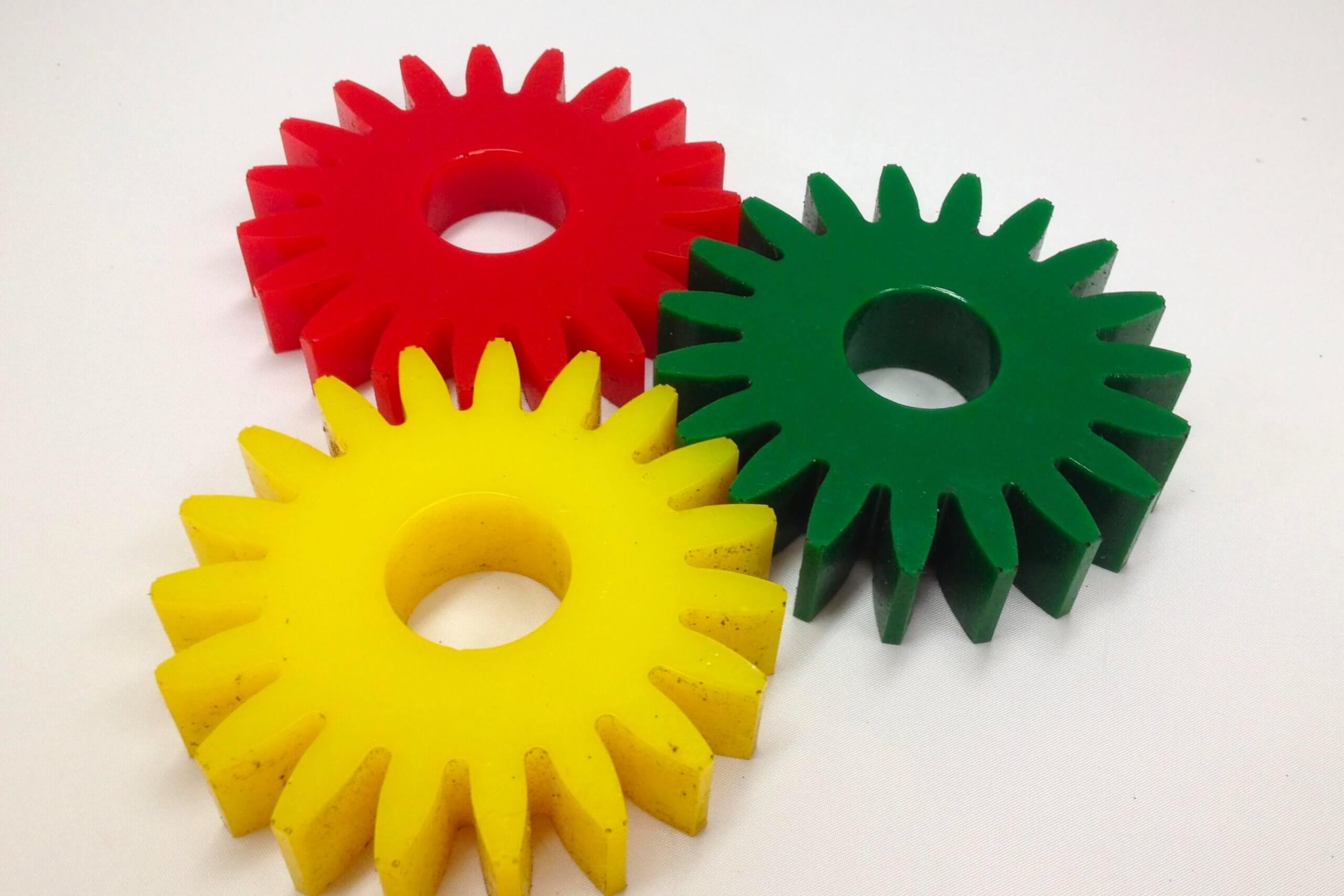 Three colorful gear-shaped objects resting on a white surface.