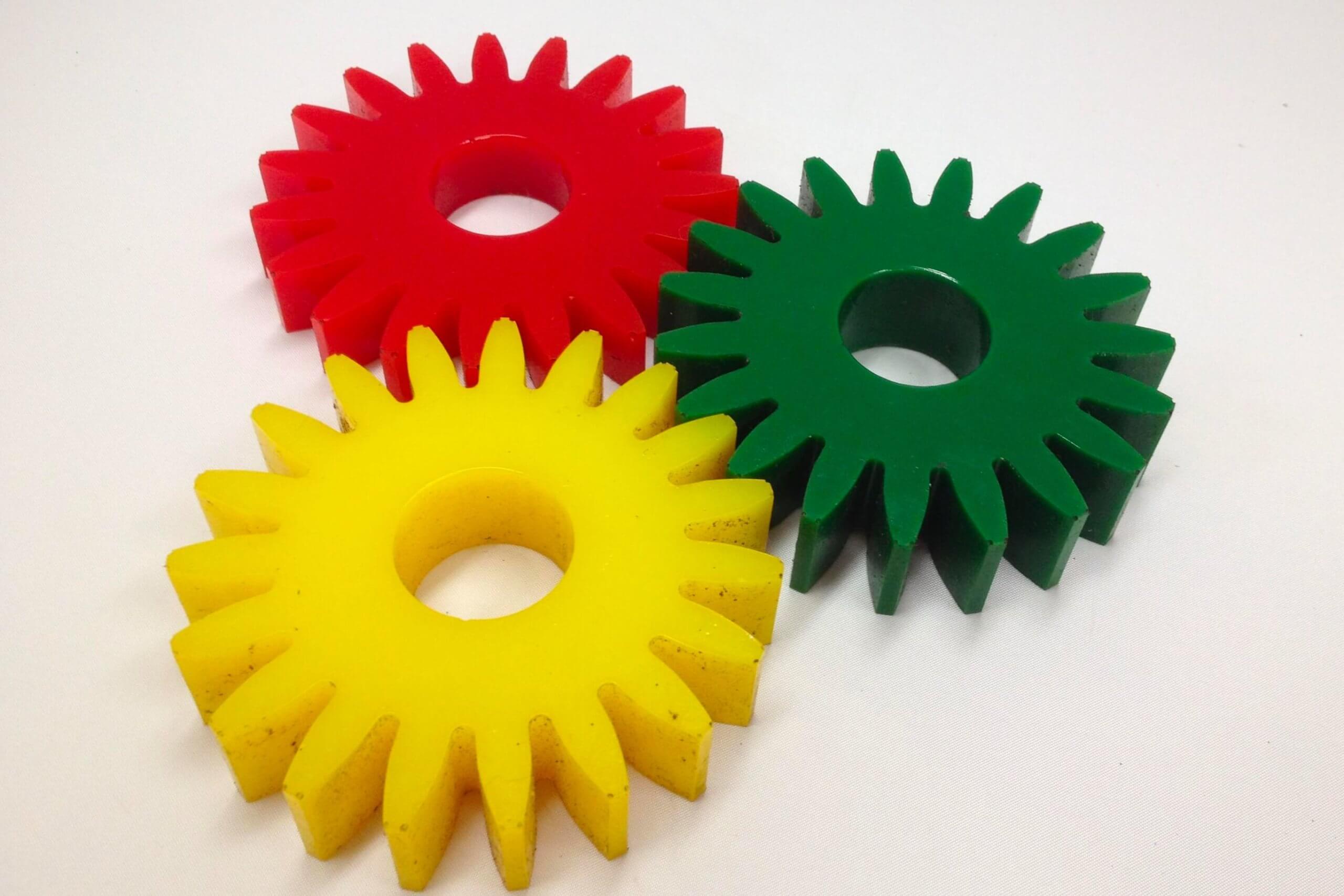 Three interlocking plastic gears in red, yellow, green.