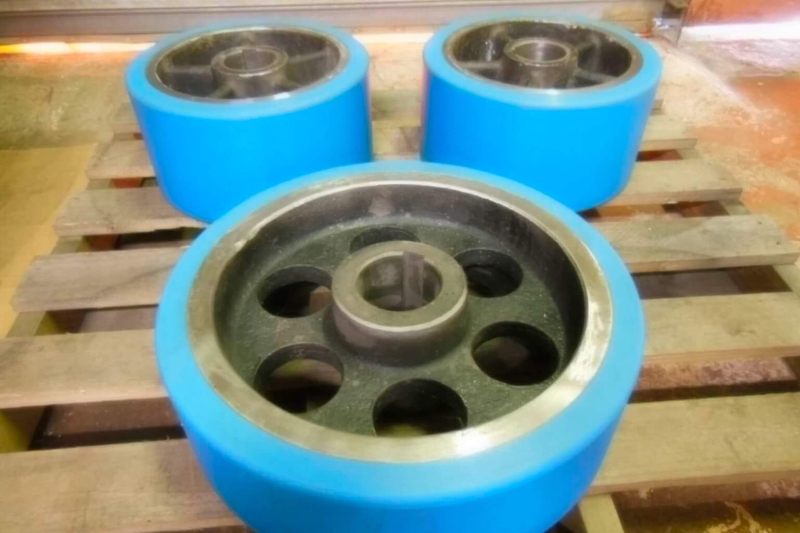 Blue industrial wheels resting on a wooden pallet.