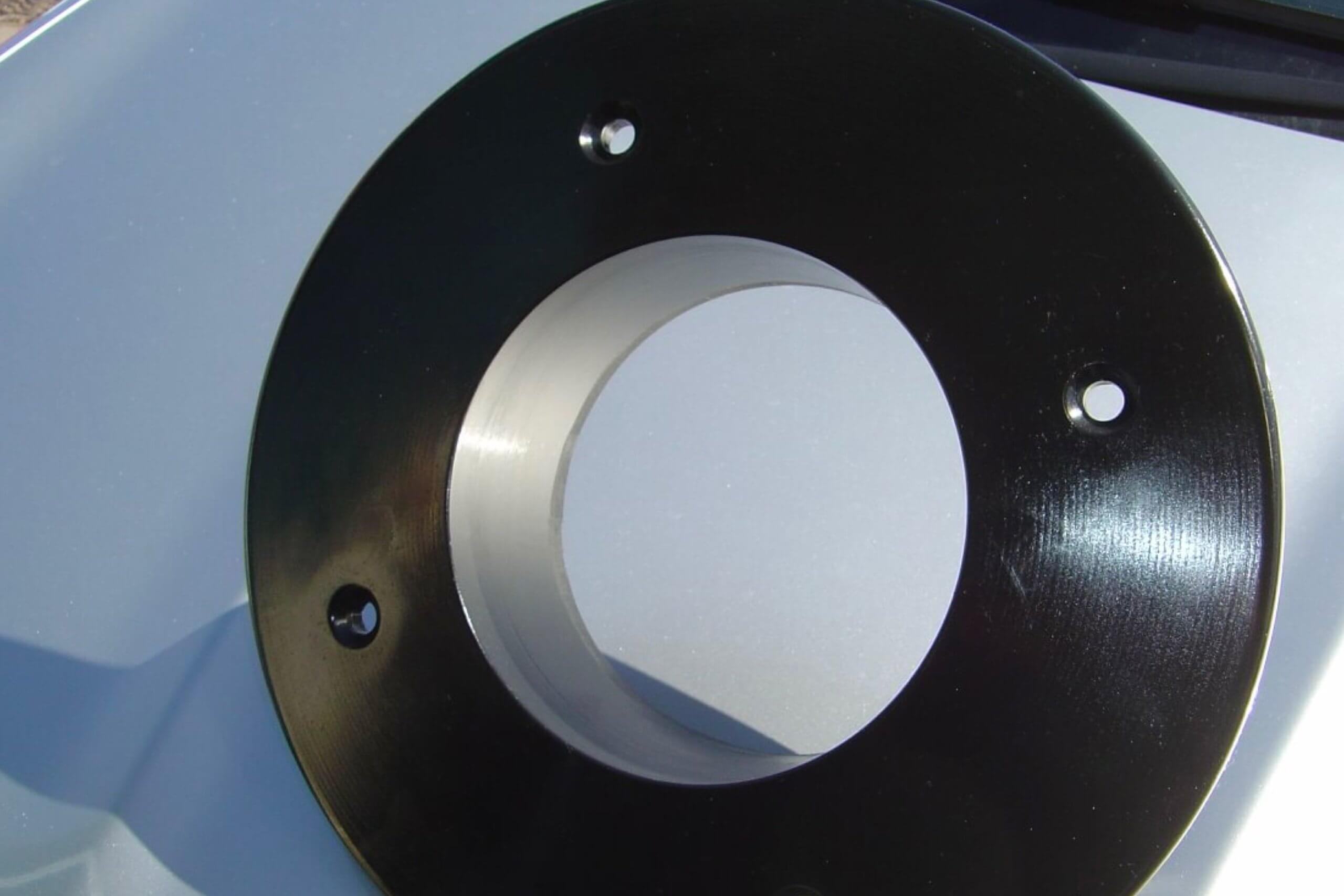 Circular metal disk with holes, resting on light surface.