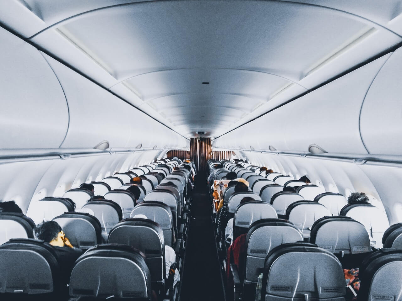 Airplane cabin filled with seated passengers in flight.