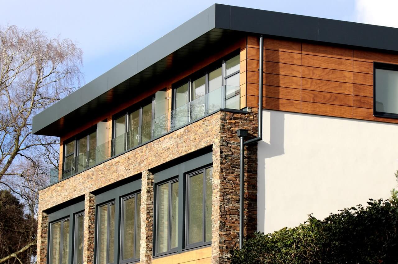 Modern house with large windows, surrounded by trees.