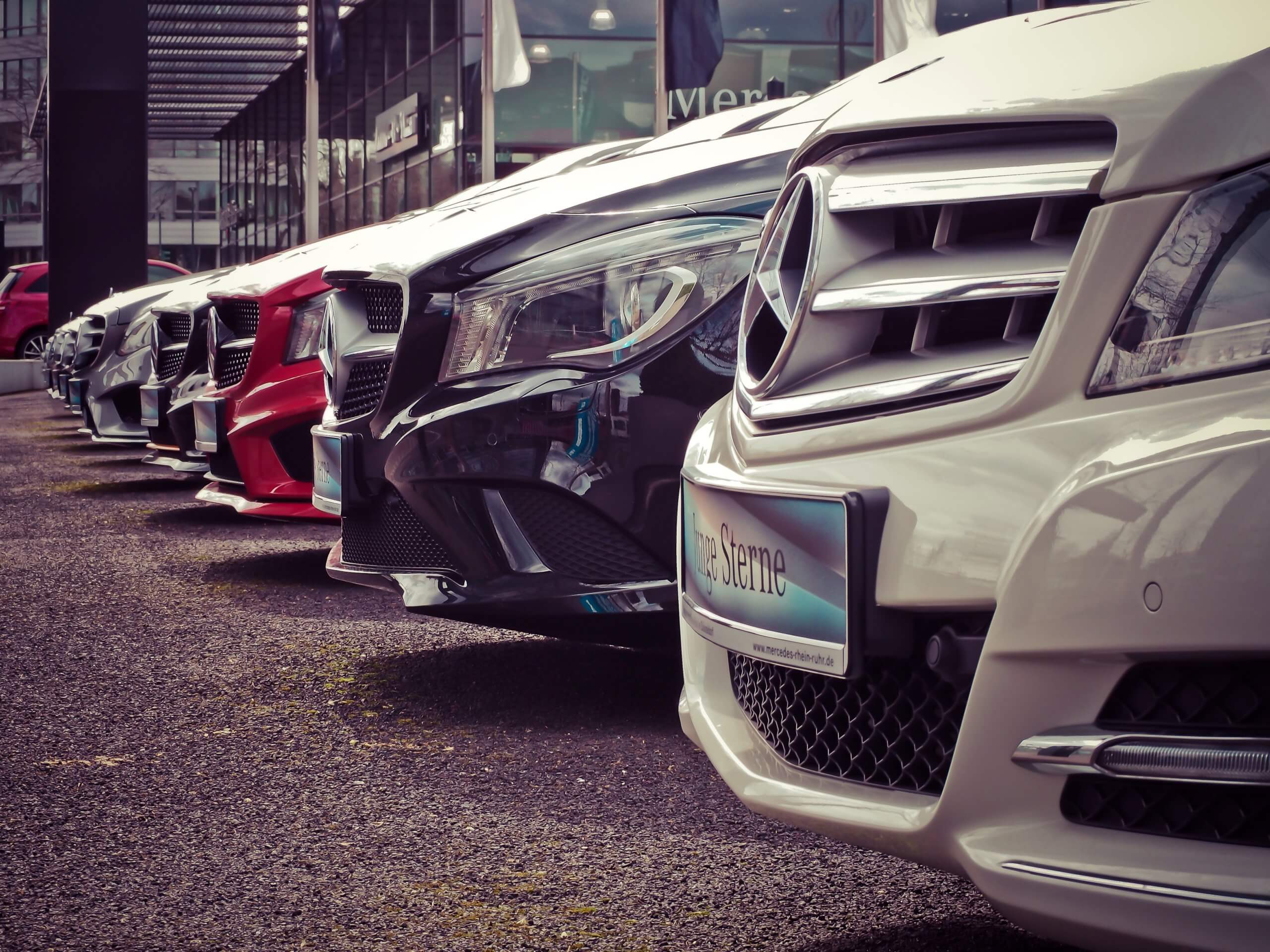 Cars parked in a row outside a dealership.