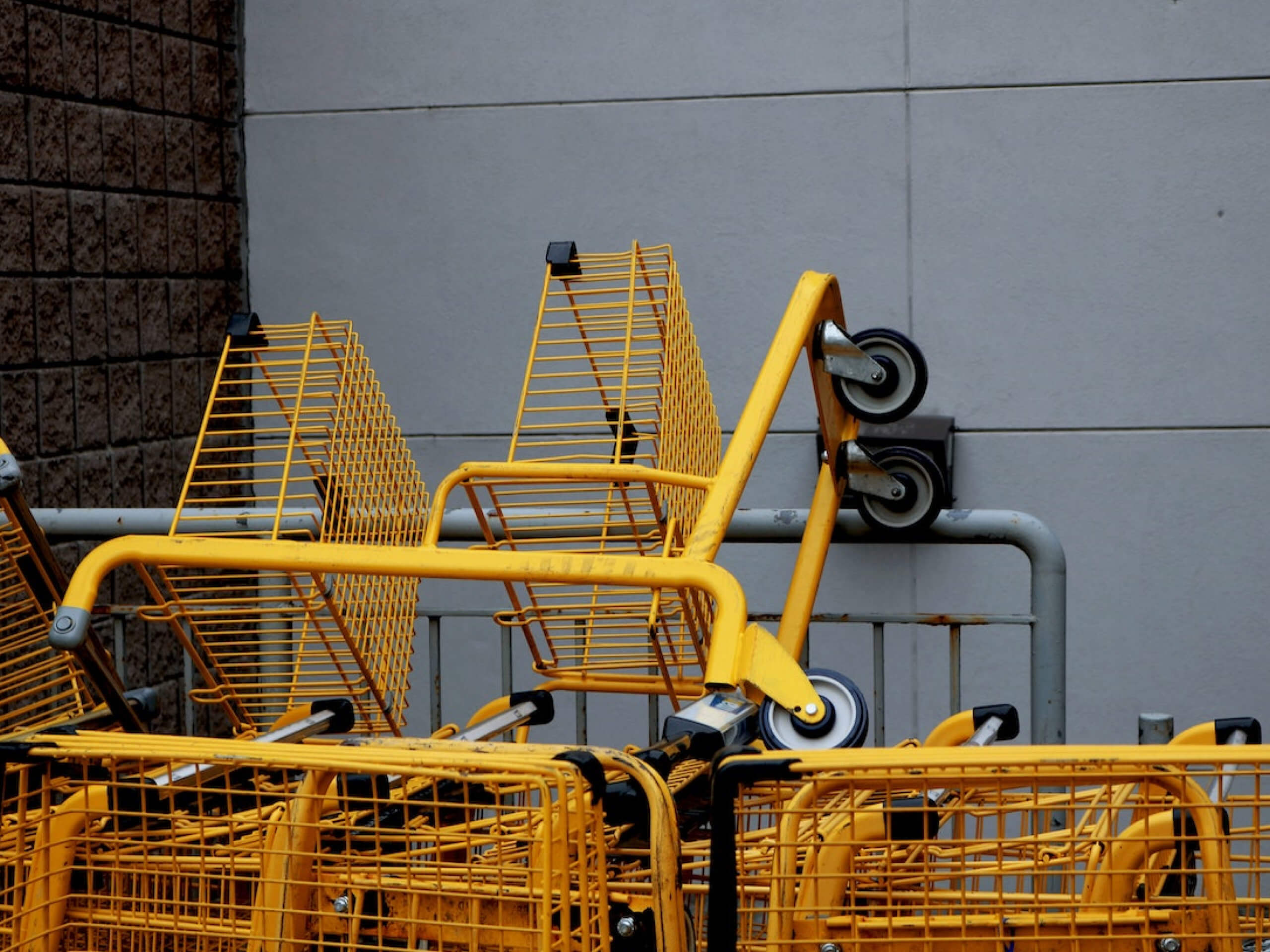 Yellow shopping carts stacked against a gray wall.