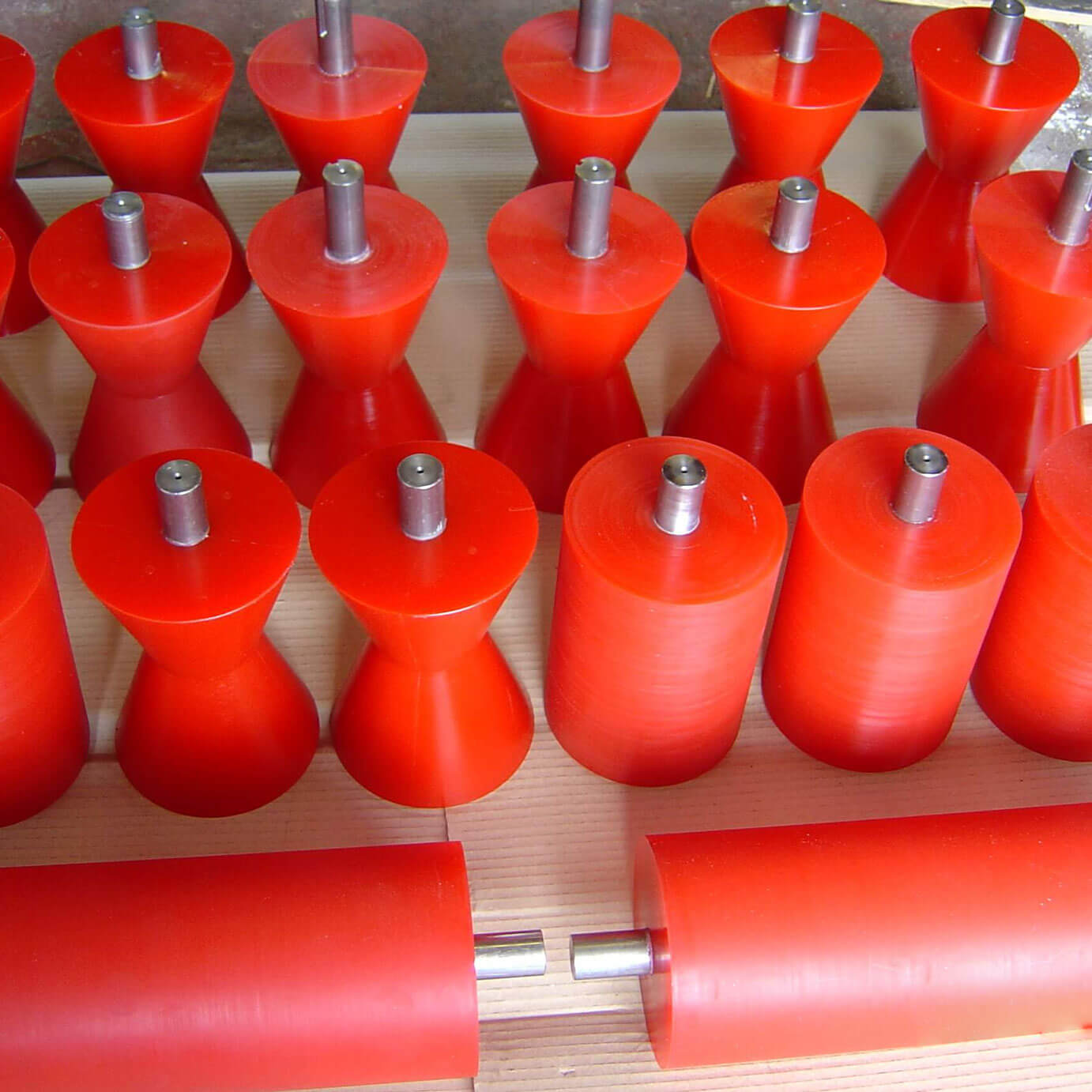 Red cylindrical and cone-shaped rollers organized on wooden surface.