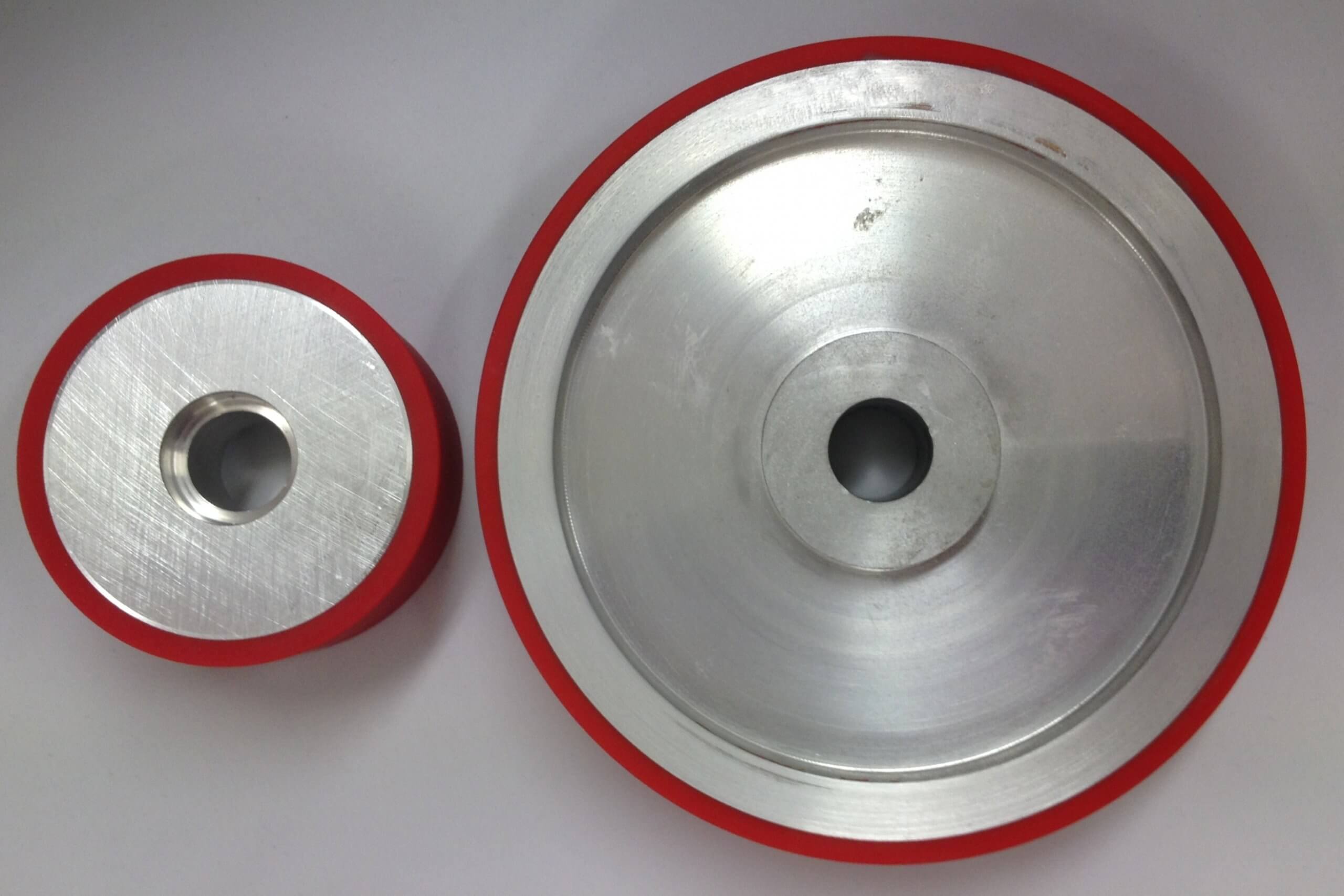 Two metal pulleys with red rims on white background.