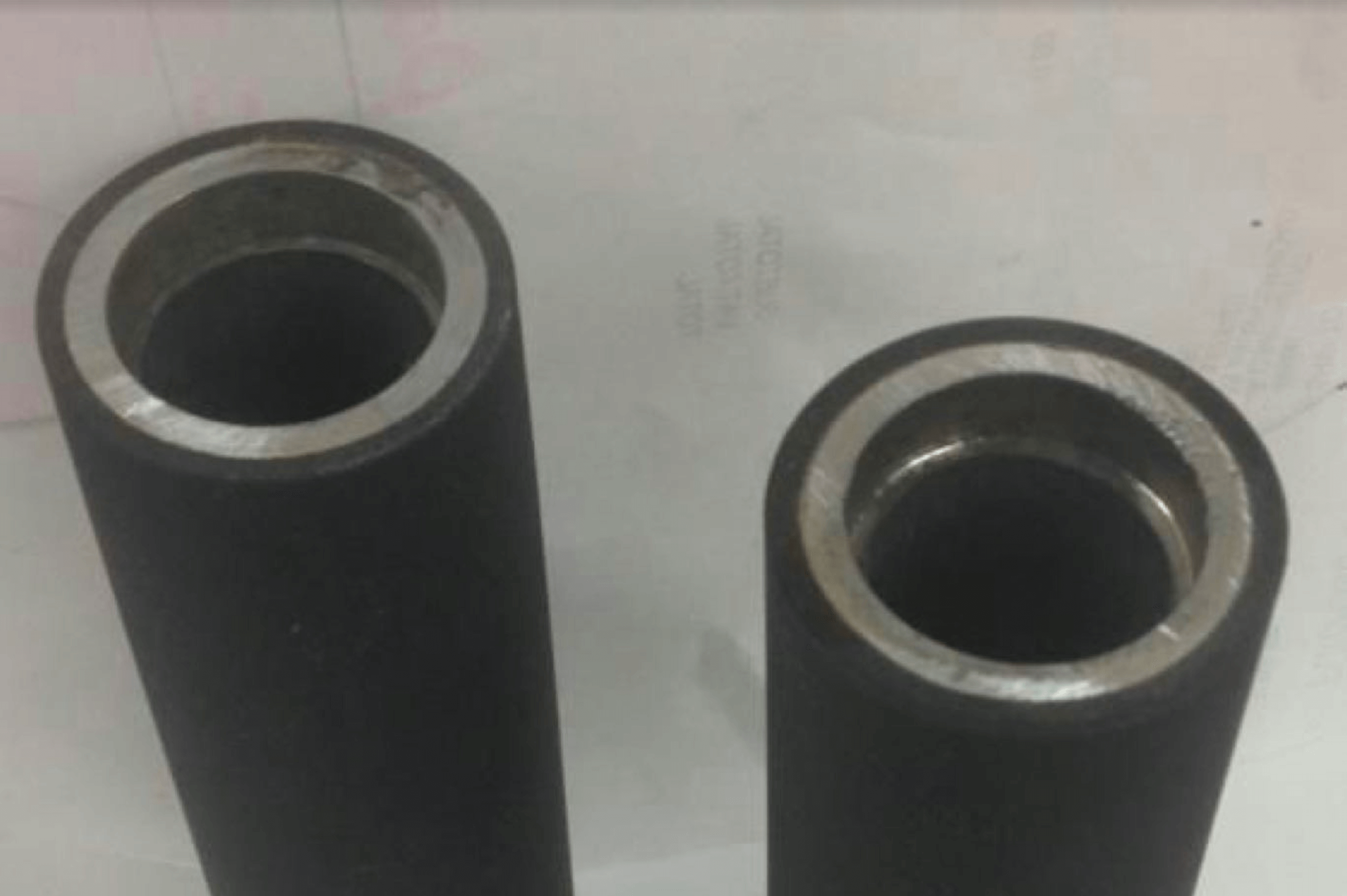 Two cylindrical metal pipes stand upright on paper.