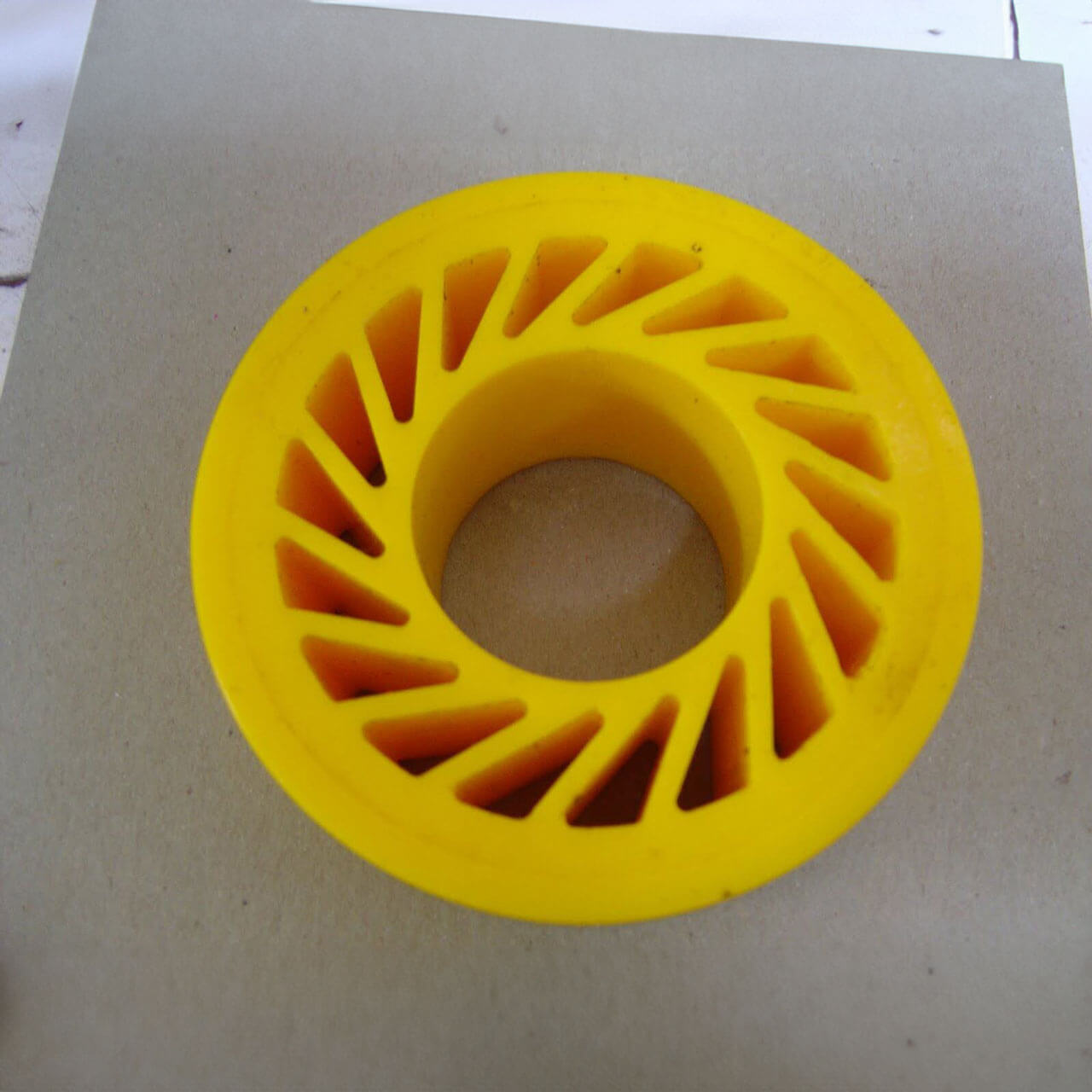 Yellow circular object with triangular cutouts, placed on gray surface.
