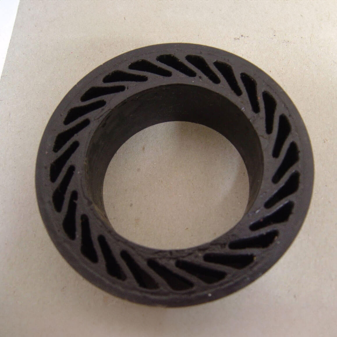Metal ring with spiral cutouts, resting on white surface.
