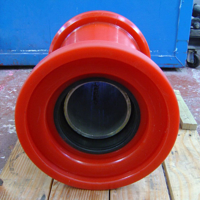 Red cylinder resting on wooden surface, blue background.