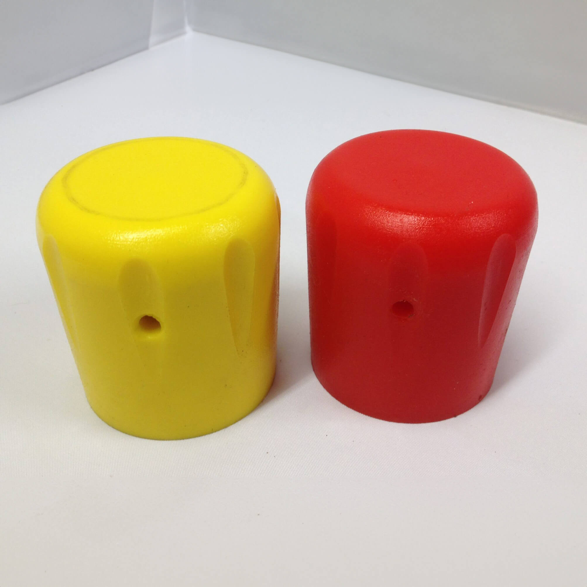 Yellow and red caps standing upright on white surface.