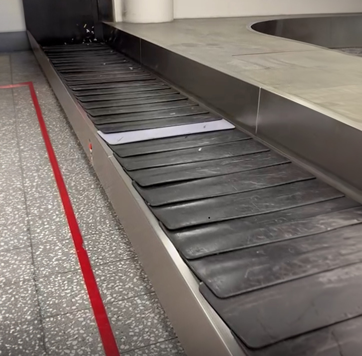 Empty luggage conveyor belt moving in an airport terminal.