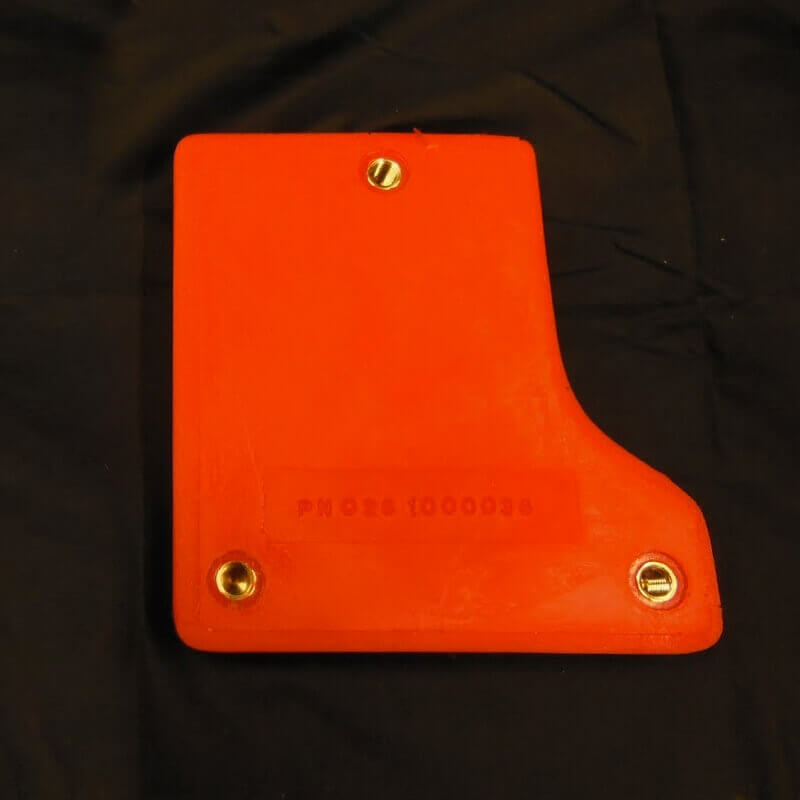 Orange plastic object with bolts on a dark surface.
