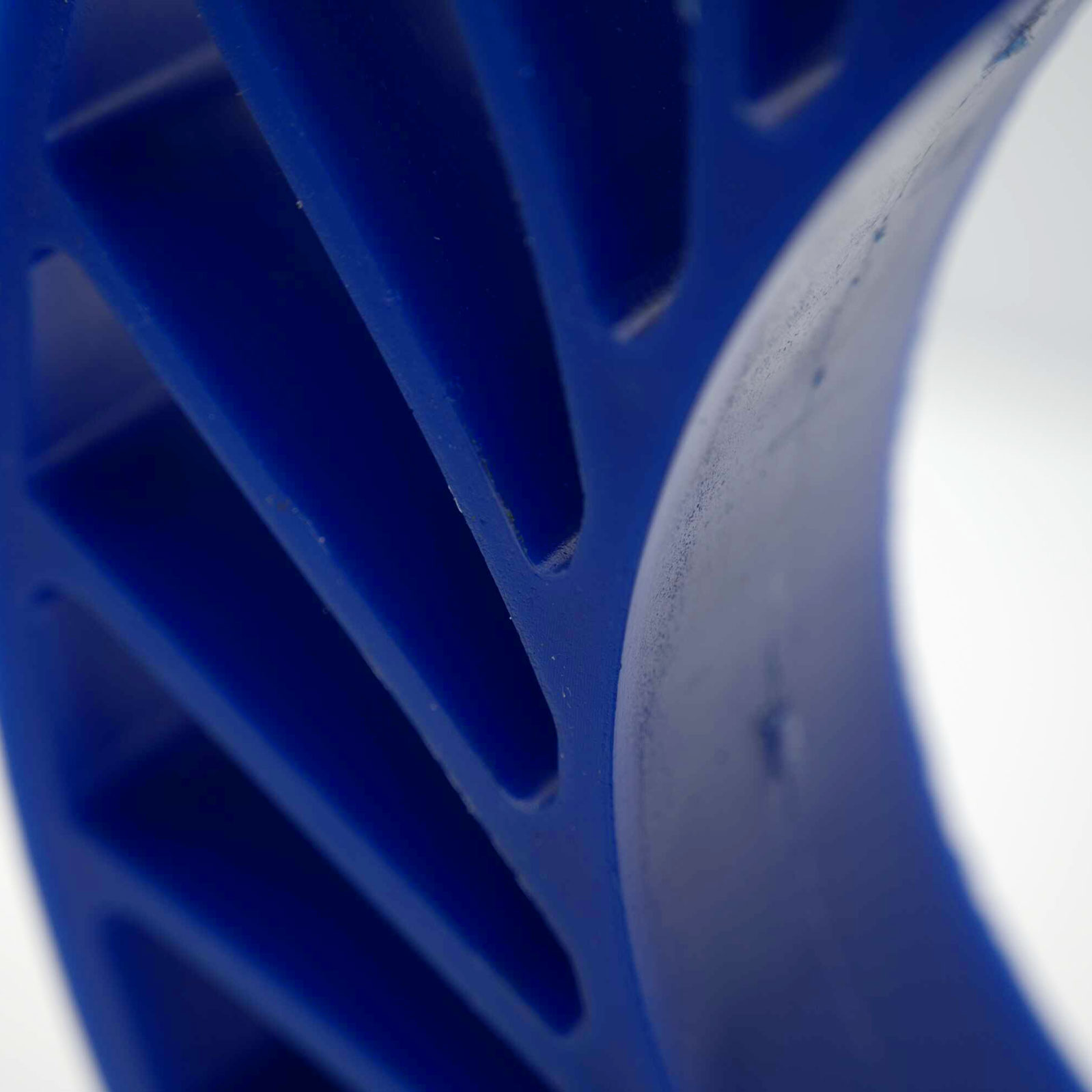 Blue, ribbed wheel standing against a neutral background.