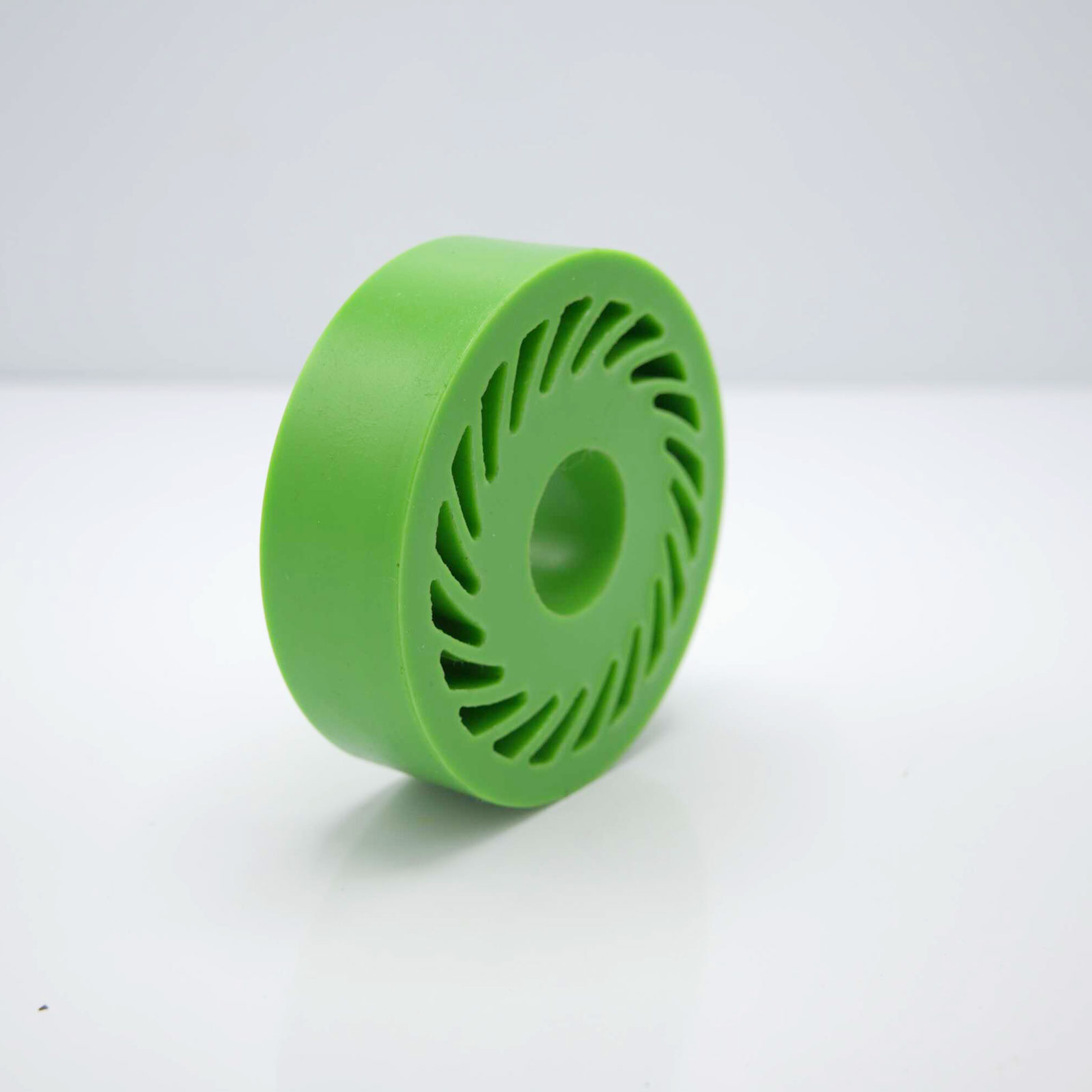 Green circular object with slotted design, on white surface.