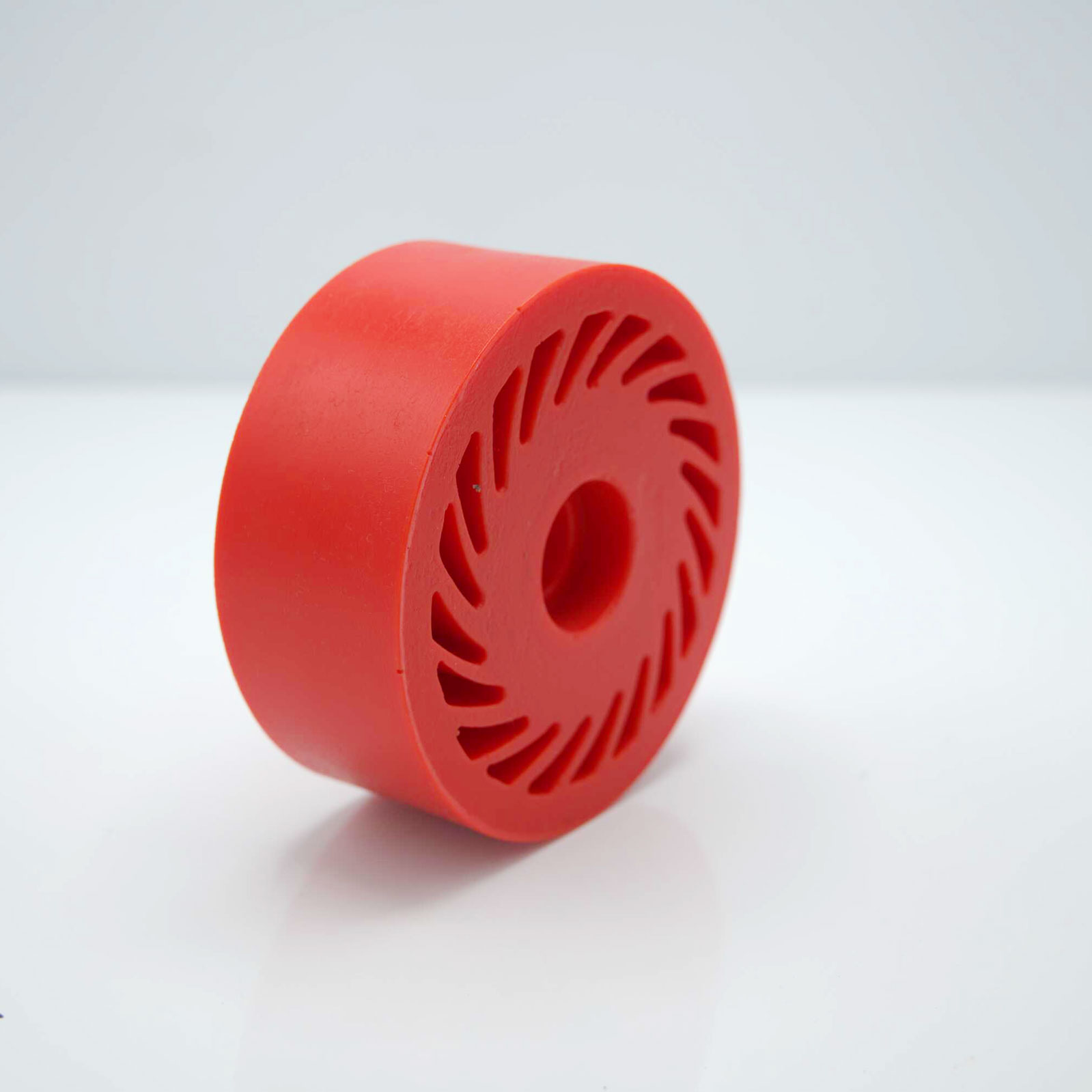 Red rubber wheel standing on smooth, reflective surface.