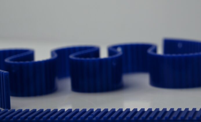 Blue plastic gears coiled on a reflective surface.